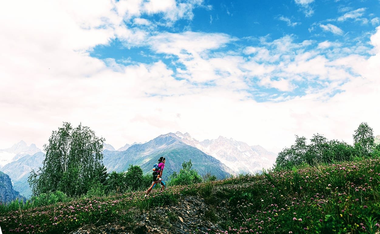 Wide mountain landscape with Trisha running on a distant ridge